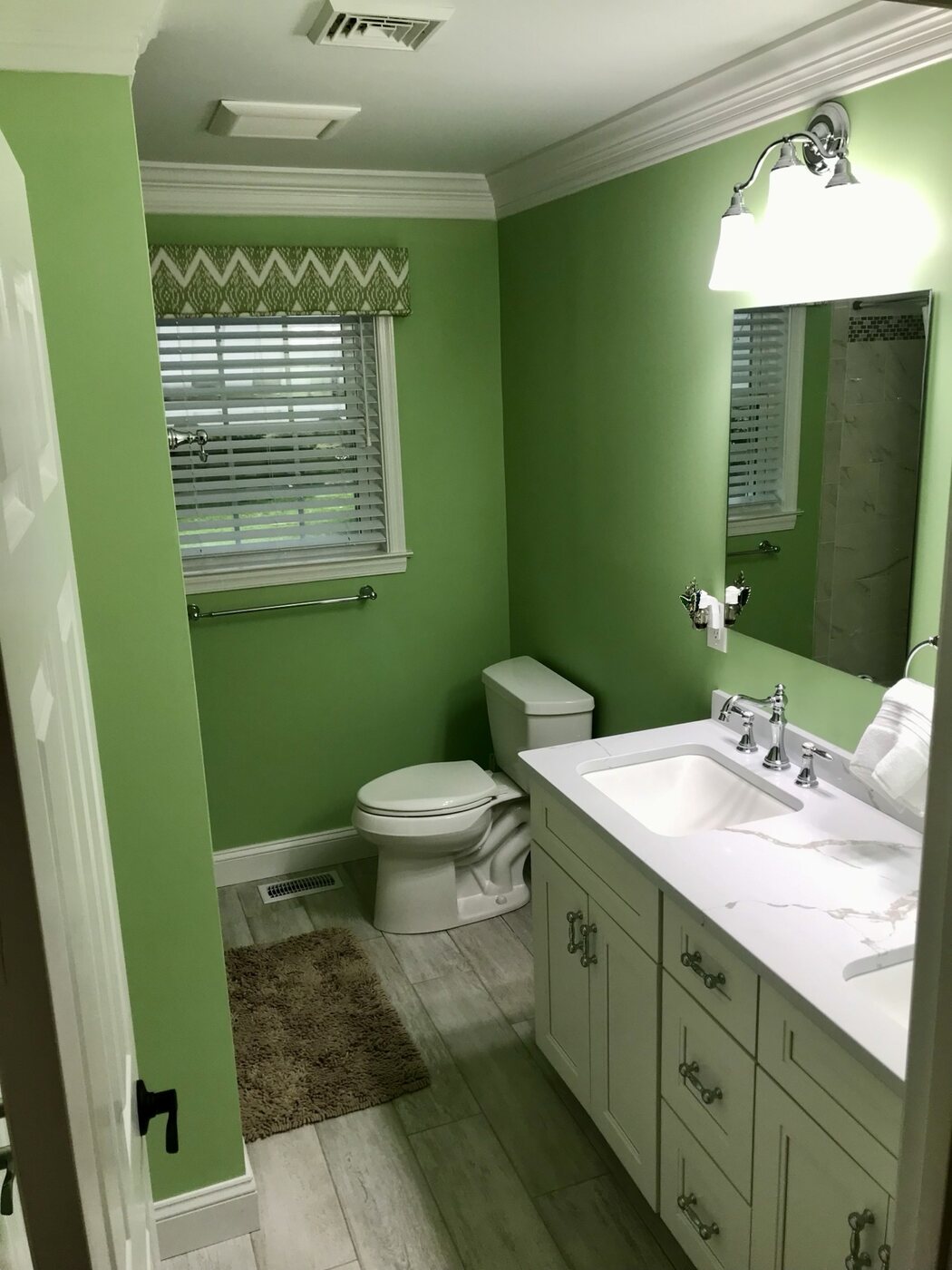 Bathroom 5 with white vanity, green walls, and tiled tub