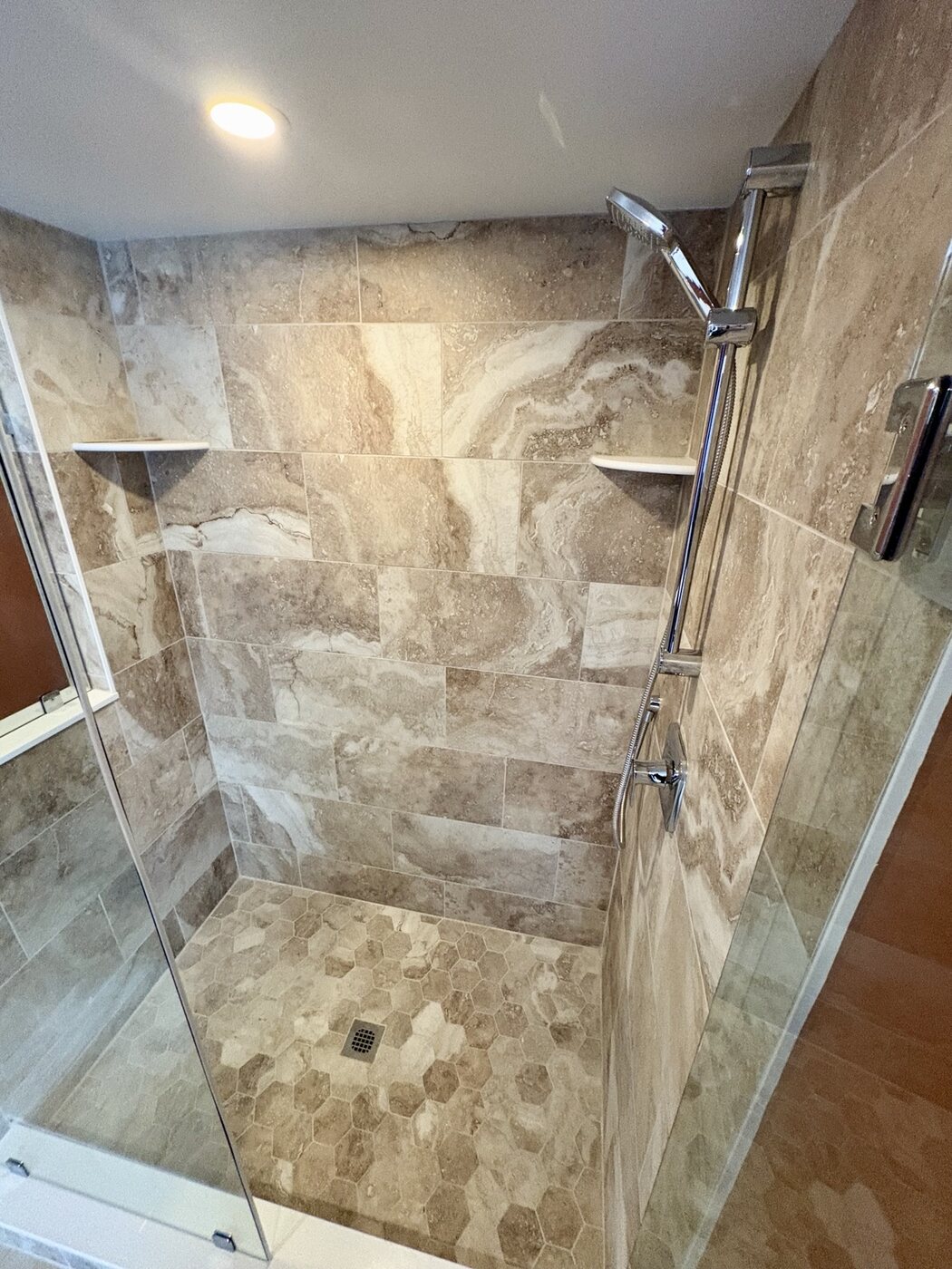 Bathroom 1 shower tile, pebble floor, shelves, and handheld fixture