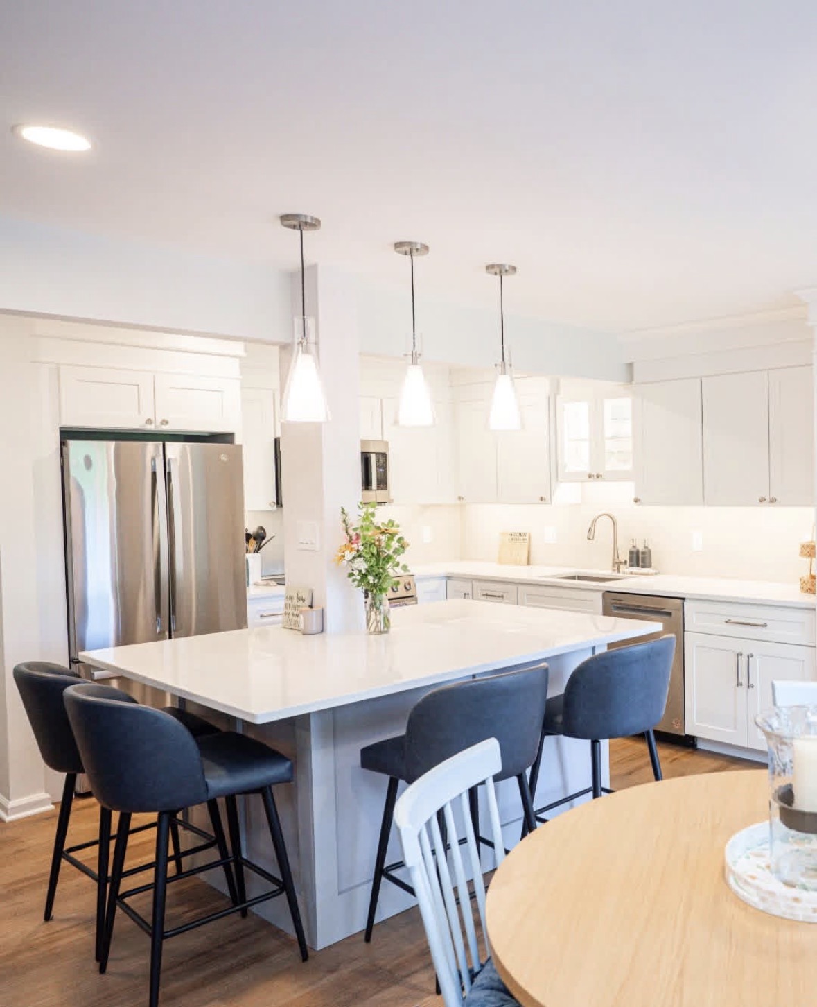 Renovated kitchen with white cabinets and island seating, wide view
