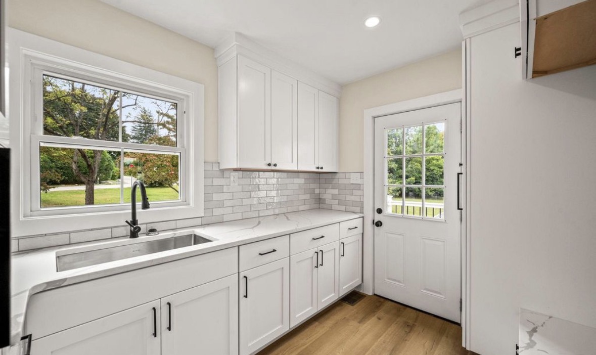 Finished kitchen cabinetry, sink, counters, and exterior door