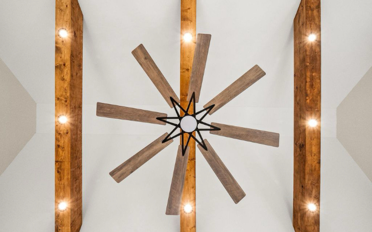 Exposed wood beams and statement ceiling fan in the addition