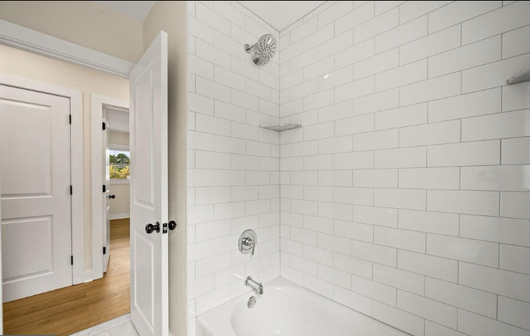 Full bathroom with tiled tub and shower surround