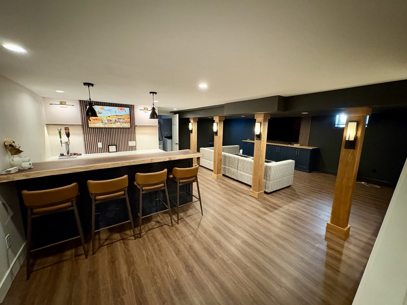 Completed Downingtown basement with live-edge bar, media lounge, and custom wood columns