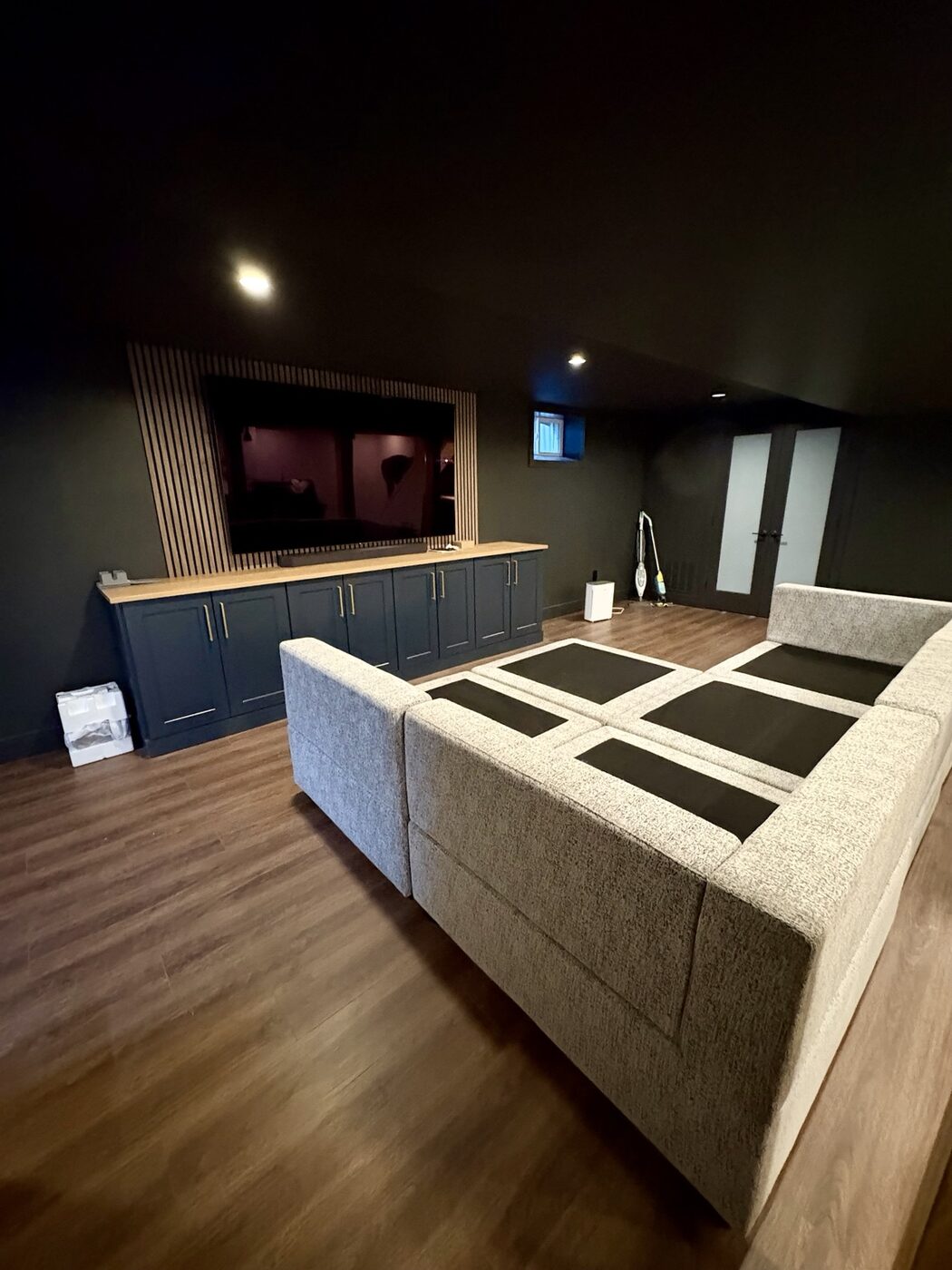 Finished basement lounge with sectional seating and wood-look flooring