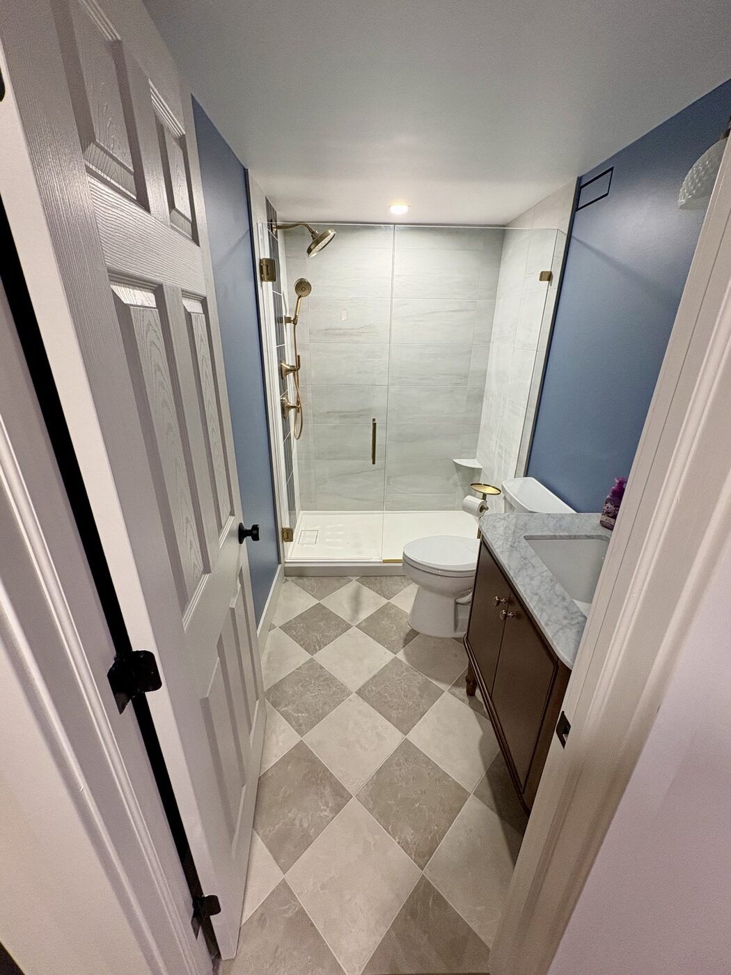 Full basement bathroom with tiled shower and checkerboard floor