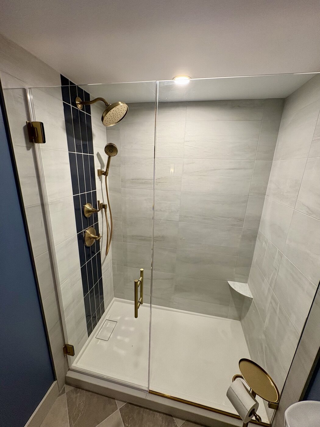Glass-enclosed basement shower with large-format tile