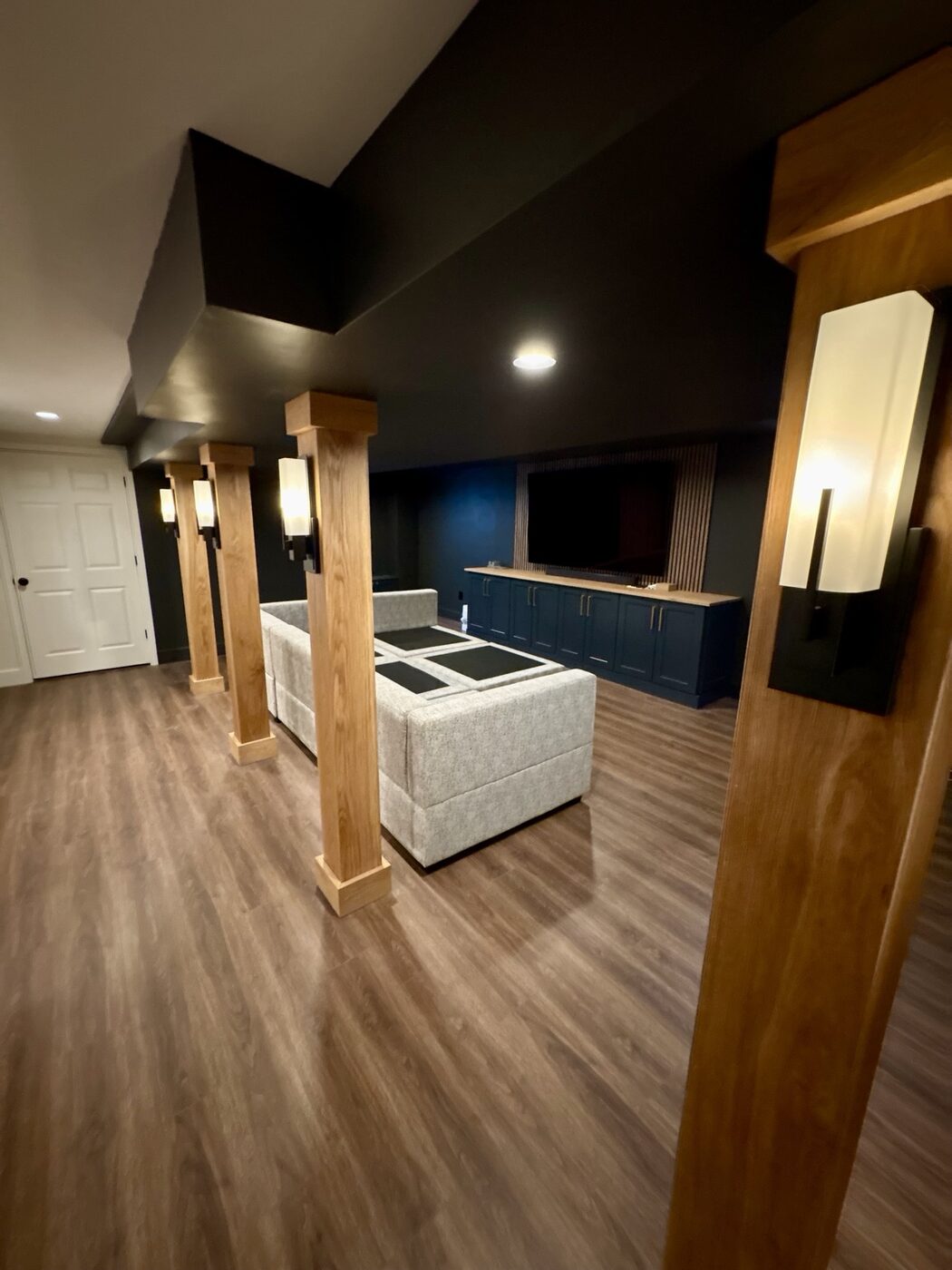 Wood-wrapped basement columns with modern wall sconces